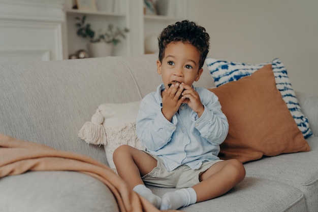 Hambre lindo niño afroamericano comiendo cupcake mientras pasa tiempo en casa