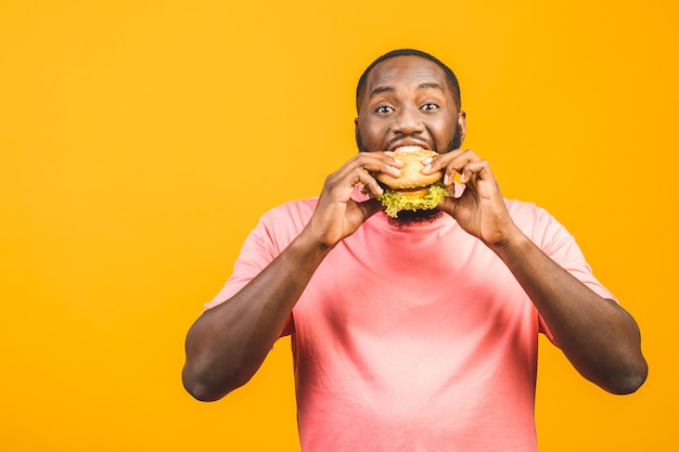 Hamburger antropófago afro-americano novo isolado sobre a parede amarela.