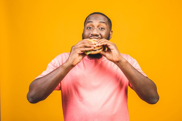 Hamburger antropófago afro-americano novo isolado sobre a parede amarela.