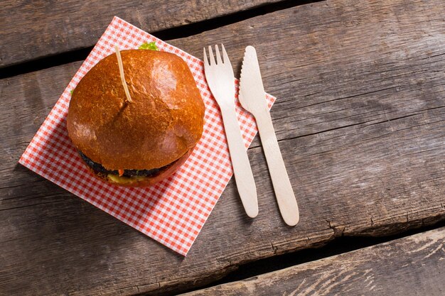 Hamburger auf Stick und Besteck Burger auf gealtertem Holztisch frische und warme Brötchen essen, während es warm ist