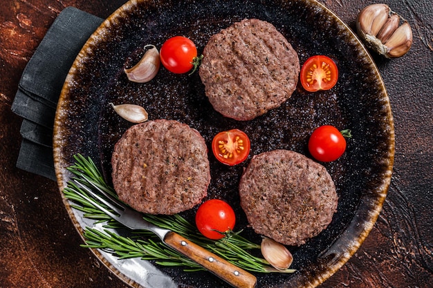 Hamburger gegrillte Fleischkotelettpastetchen mit Kräutern. Dunkler Hintergrund. Ansicht von oben.