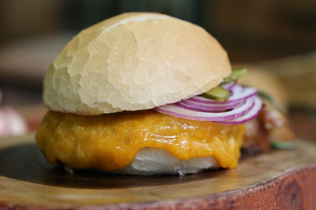 Hamburger gemacht auf dem Grillgrill mit Käsespeck-Zwiebelgurke auf hölzernem Hintergrund