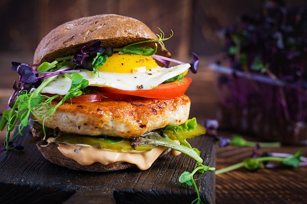 Hamburger mit Chicken Burger, Tomaten, eingelegter Gurke und Spiegelei