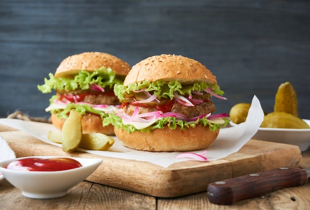 Hamburger mit eingelegten Gurken, Zwiebeln, Käse, Salat und Tomatensauce