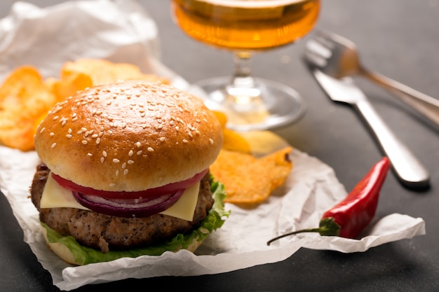 Hamburger mit Fleischkotelett. Kartoffelchips und Bier