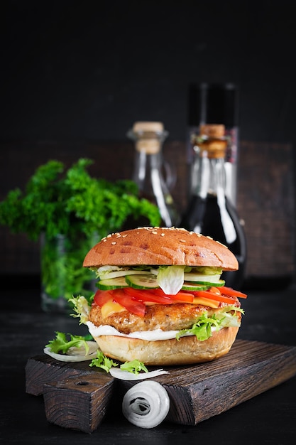 Hamburger mit Hühnchen Burger Fleisch Käse Tomaten Gurke und Salat auf Holzhintergrund Leckerer Burger Nahaufnahme