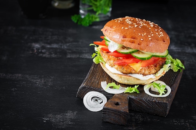 Hamburger mit Hühnchen Burger Fleisch Käse Tomaten Gurke und Salat auf Holzhintergrund Leckerer Burger Nahaufnahme