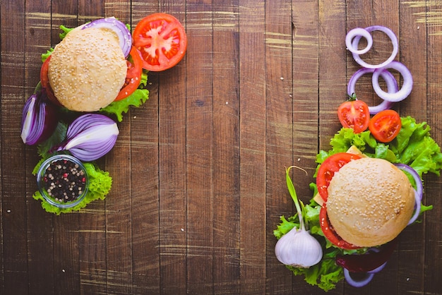 Hamburger mit Käsefleischtomaten und -zwiebeln und -kräutern auf Draufsicht des hölzernen Hintergrundes Freier Platz