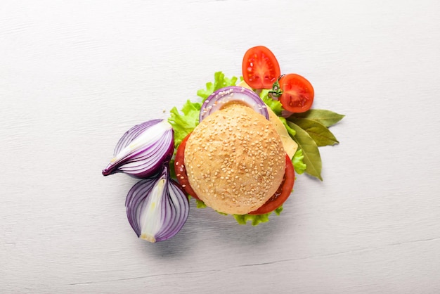 Hamburger mit Käsefleischtomaten und -zwiebeln und -kräutern auf Draufsicht des hölzernen Hintergrundes Freier Platz