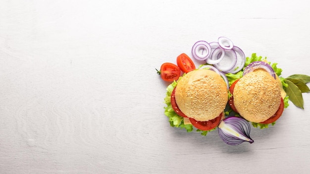 Hamburger mit Käsefleischtomaten und -zwiebeln und -kräutern auf Draufsicht des hölzernen Hintergrundes Freier Platz