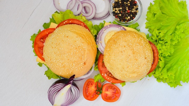 Hamburger mit Käsefleischtomaten und -zwiebeln und -kräutern auf Draufsicht des hölzernen Hintergrundes Freier Platz