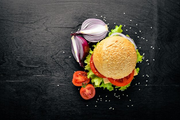 Hamburger mit Käsefleischtomaten und -zwiebeln und -kräutern auf Draufsicht des hölzernen Hintergrundes Freier Platz