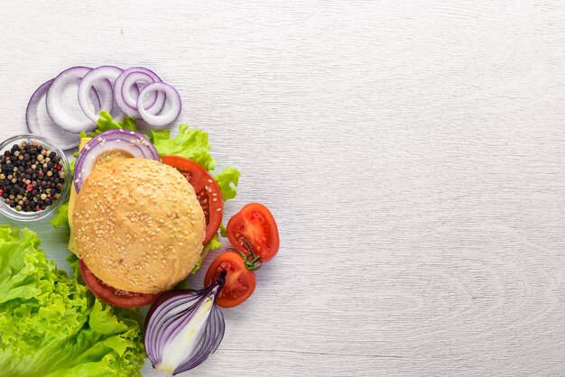 Hamburger mit Käsefleischtomaten und -zwiebeln und -kräutern auf Draufsicht des hölzernen Hintergrundes Freier Platz