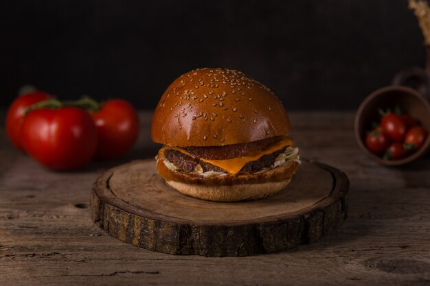 Hamburger mit Pommes frites, Ketchup, Senf und frischem Gemüse auf einem Holzbrett.