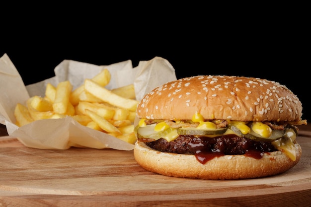 Hamburger mit Pommes frites und Soße Hölzerner Hintergrund