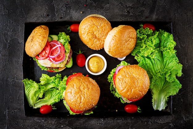 Hamburger mit Rindfleischfleischburger und Frischgemüse auf dunklem Hintergrund.