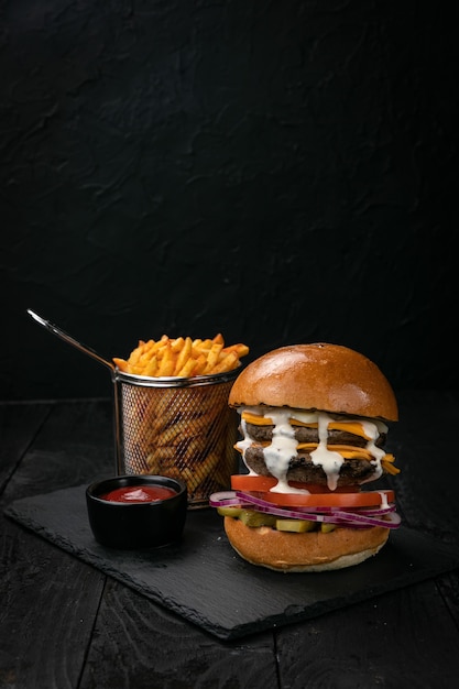 Hamburger mit Sauce und Pommes Frites auf einem dunklen Holztisch