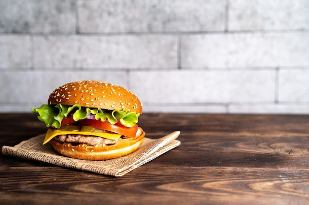 Hamburger mit Schnitzel-Tomate und Käse auf einem dunklen Holztisch und Papierkopierraum