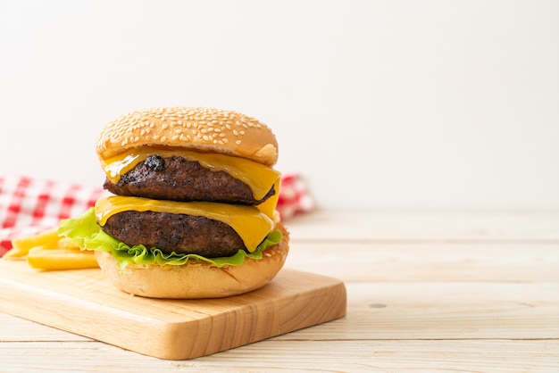 Hamburger oder Beef Burger mit Käse und Pommes Frites - ungesunde Ernährungsweise