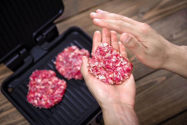 Hamburger-Pastetchen auf einem elektrischen Grill zu Hause auf rustikalem Hintergrund kochen