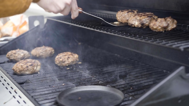 Hamburger-Rindfleischpasteten auf einem Gasgrill kochen.