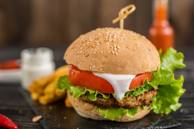 Hamburger saboroso com carne e vegetais contra um fundo escuro. comida rápida. pode ser usado como pano de fundo