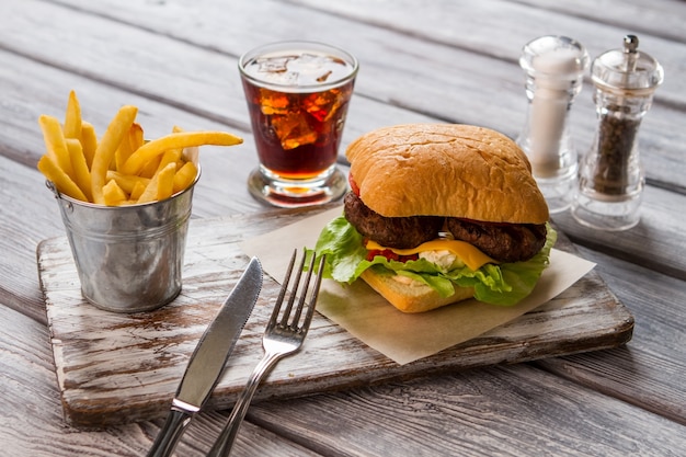 Hamburger und Pommes. Glas Cola und Gewürze. Fast Food im amerikanischen Diner. Saftiges Rindfleisch und warmer Käse.