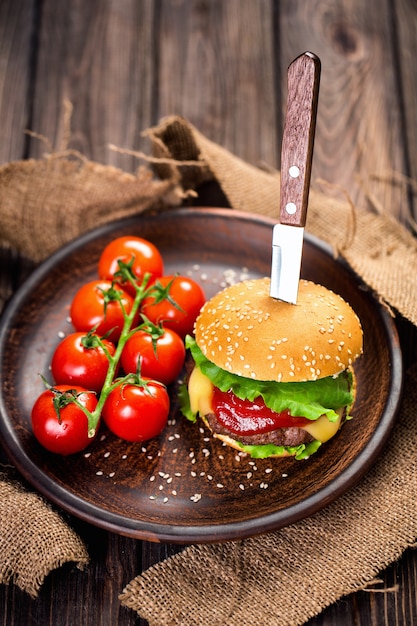 Hambúrguer apetitoso com tomates na mesa