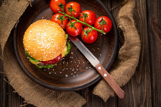 Hambúrguer apetitoso com tomates na mesa