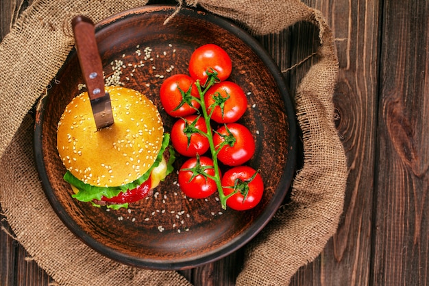 Hambúrguer apetitoso com tomates na mesa