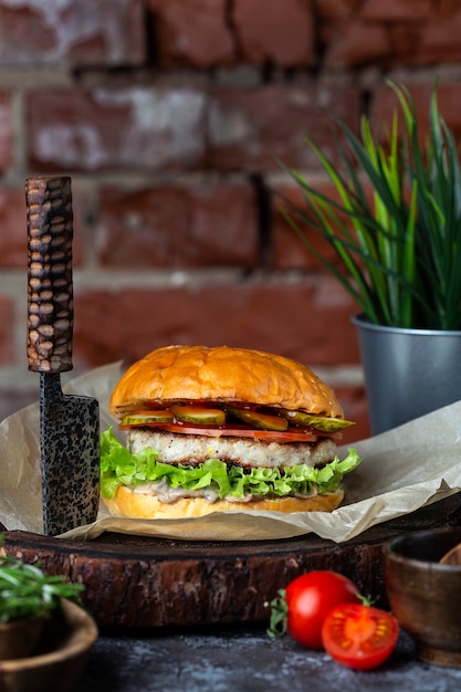 Hambúrguer caseiro saboroso com legumes frescos em uma tábua de madeira