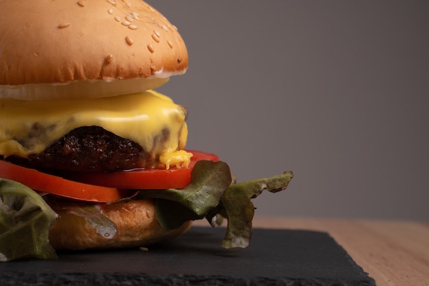 Hambúrguer caseiro saboroso fresco com legumes frescos, alface, tomate, queijo em uma placa de corte.