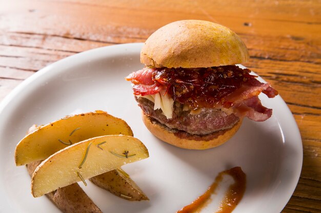 Hambúrguer com bacon, queijo e pimenta em fundo de madeira.