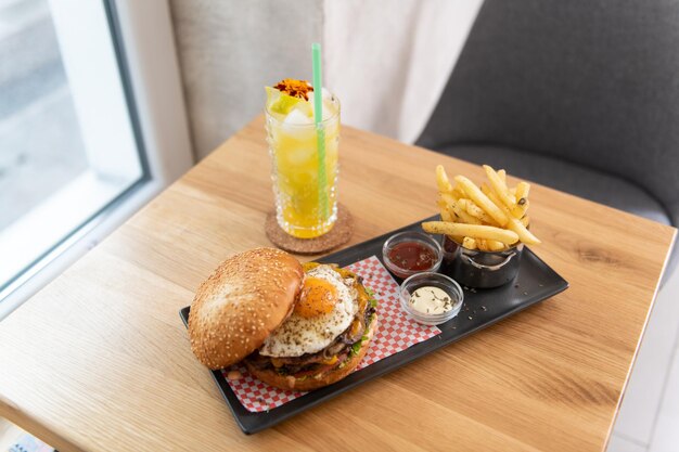 Hambúrguer com batatas fritas e molho em uma mesa escura coquetel de maracujá Mojito