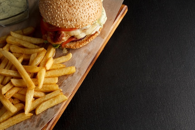 Hambúrguer com batatas fritas em um fundo preto. Detalhe de hamburguer