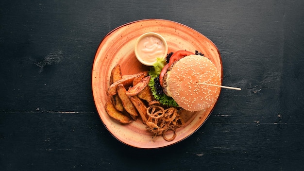 Hambúrguer com carne cebola tomate e batatas assadas No fundo antigo Espaço para cópia grátis Vista superior