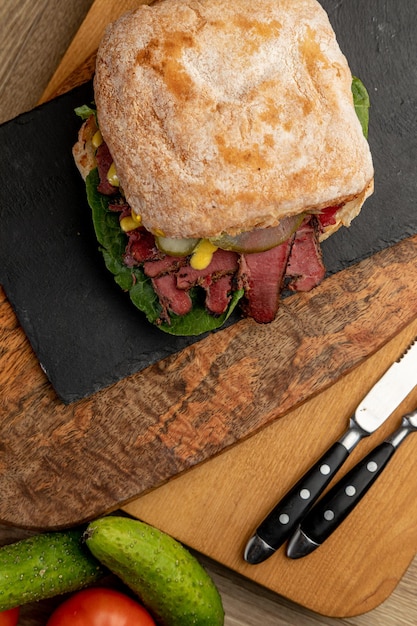 Hambúrguer com carne defumada, pepinos em conserva e ervas frescas