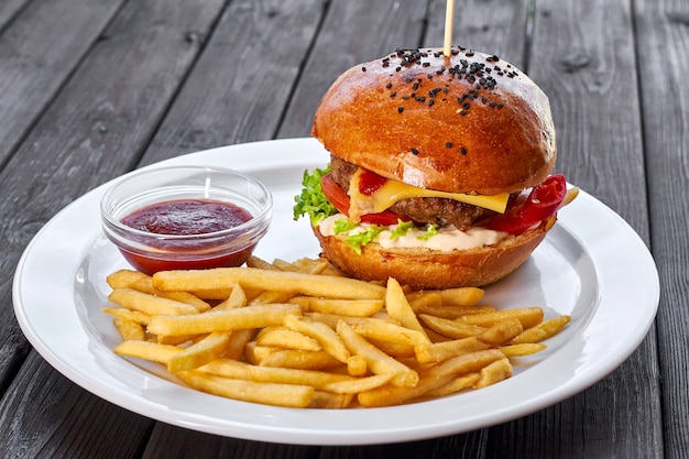 Hambúrguer com costeleta de frango, queijo, batata frita, molho de salada de tomate e ketchup em um prato