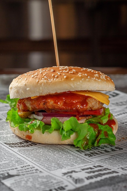 Hambúrguer com costeleta e alface em um pão de gergelim em um fundo de pedra cinza