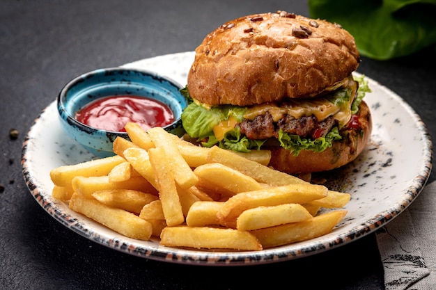 Foto hambúrguer com legumes de bife frito e queijo servido com batatas fritas e molho em um fundo escuro