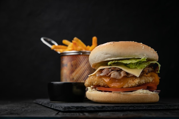 Hambúrguer com molho e batatas fritas em uma mesa de madeira escura