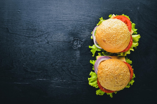 Hambúrguer com queijo carne tomate e cebola e ervas no fundo de madeira vista superior espaço livre