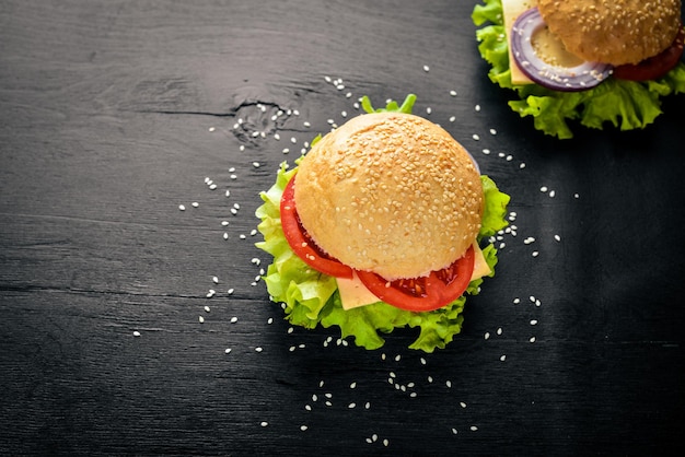 Hambúrguer com queijo carne tomate e cebola e ervas no fundo de madeira vista superior Espaço livre