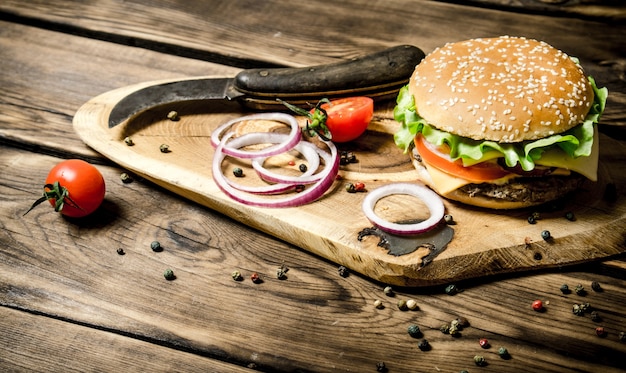 Hambúrguer cozido com legumes, queijo e carne. Na mesa de madeira.