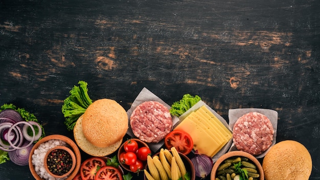 Hambúrguer cru Cozinhar um hambúrguer com carne Em um fundo preto de madeira Vista superior Espaço para cópia grátis