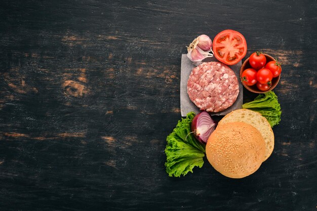 Hambúrguer cru cozinhar um hambúrguer com carne em um fundo preto de madeira vista superior espaço para cópia grátis