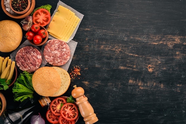 Hambúrguer cru Cozinhar um hambúrguer com carne Em um fundo preto de madeira Vista superior Espaço para cópia grátis