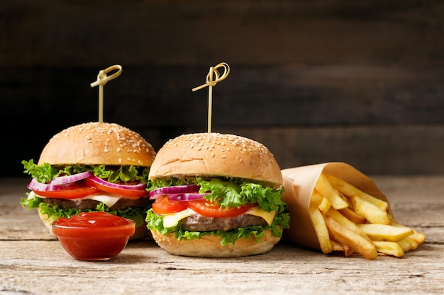 Hambúrguer de carne apetitosa suculenta batatas fritas dois molhos em uma mesa de madeira Hambúrguer caseiro de fast food americano