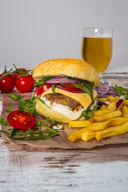 Hambúrguer de carne caseiro com queijo e batatas fritas no fundo de madeira