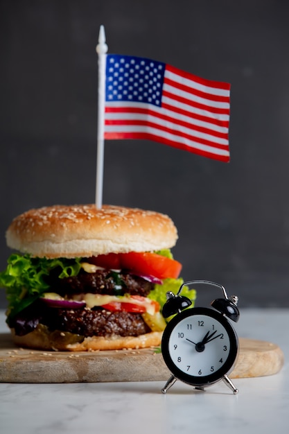 Hambúrguer de carne com bandeira EUA na bandeja e despertador